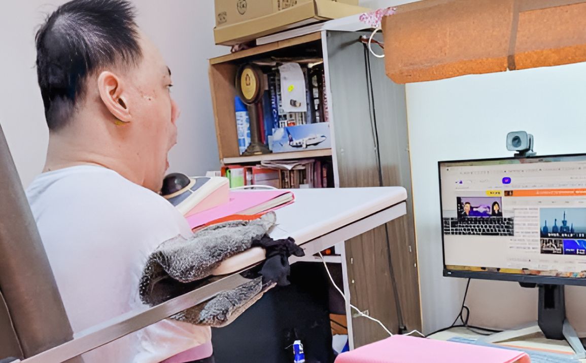 銘哲用下巴推動軌跡球來操作電腦